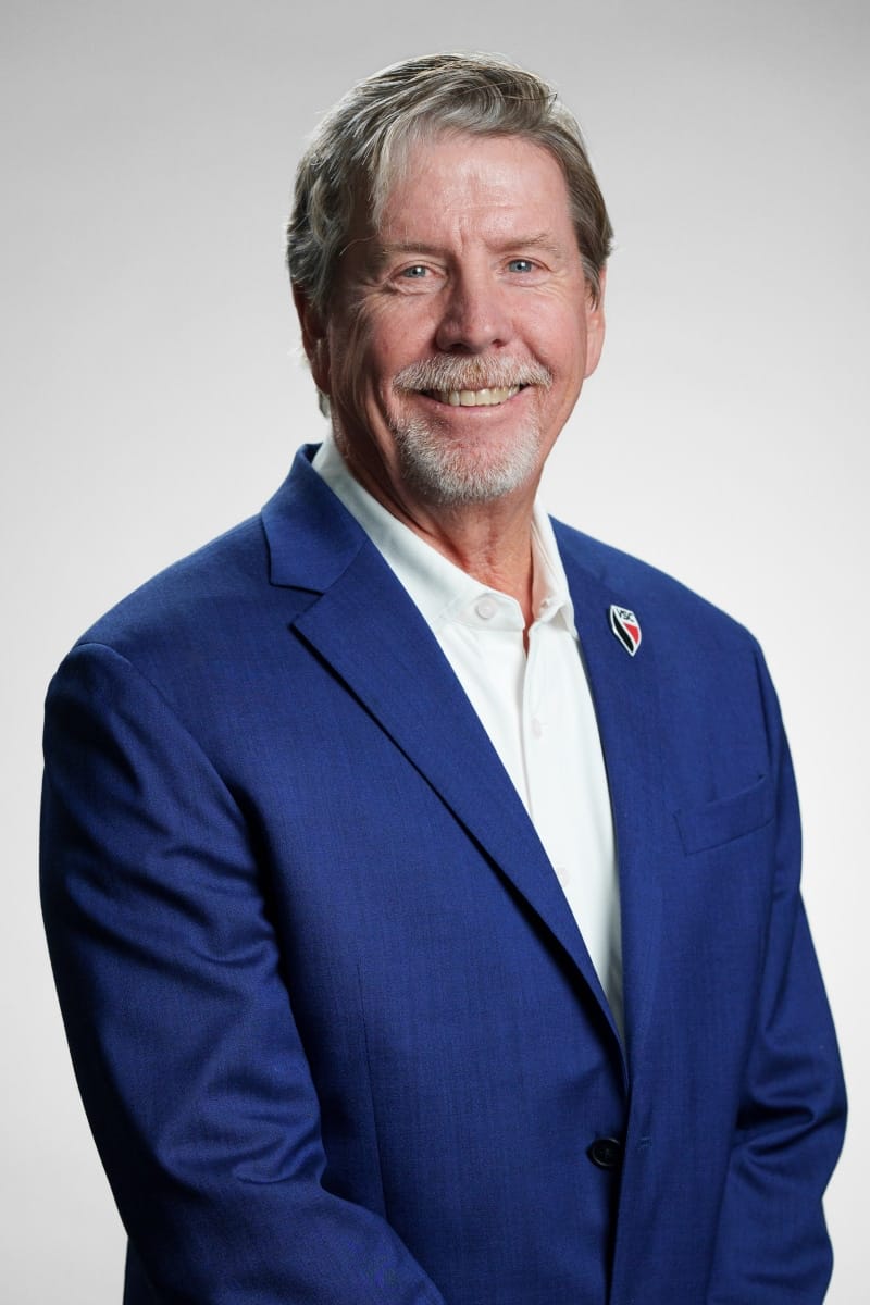 Professional portrait of a smiling company executive in a blue blazer.